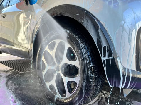 A silver car at a car wash after cleaning with active foam