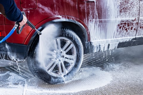 Washing red car in hand car wash with lots of foam